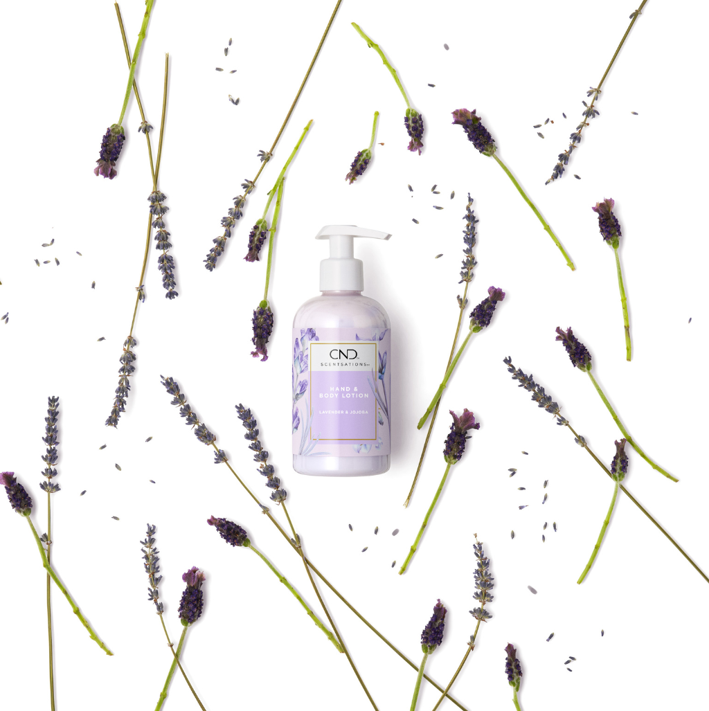 Lavender body lotion in pump bottle with lavender flowers scattered behind the bottle.