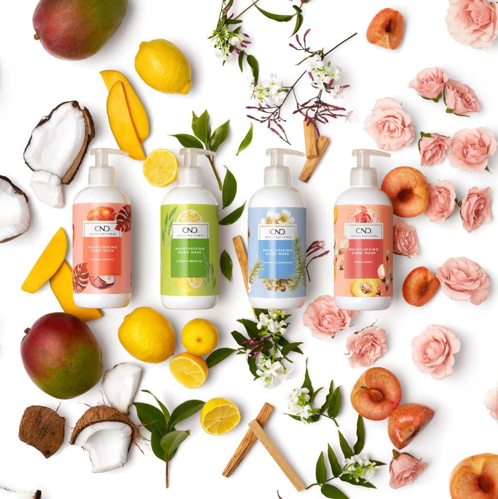 Four pump bottles with bodywash on fruit, rose background to showcase the ingredients.